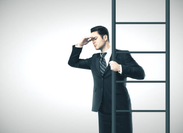 istock Young businessman standing on ladder 1211036486