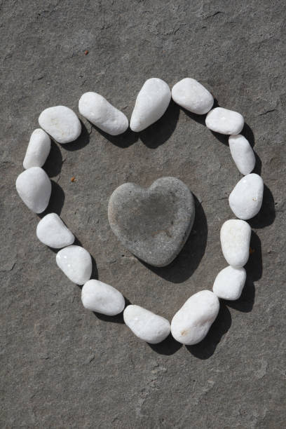 istock white stones around black stone in shape of heart 1211037038