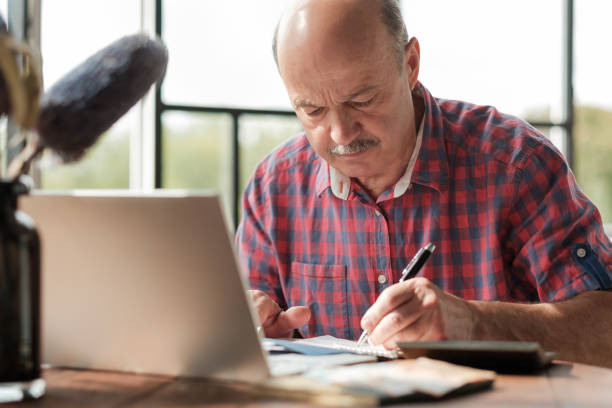 istock Mature hispanic man sitting at his desk and taking notes 1211039086