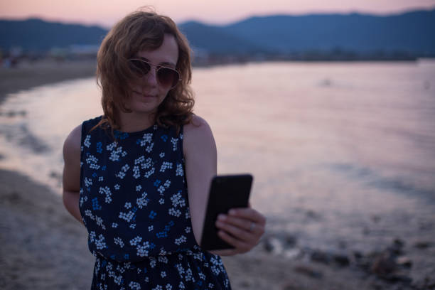 istock Young woman texting on a beach 1211040526