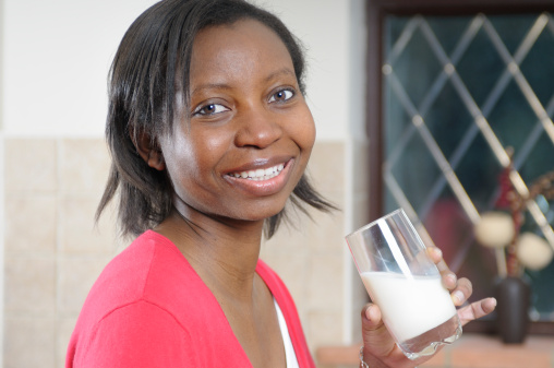 African American woman enjoying a glass of milk in the kitchen