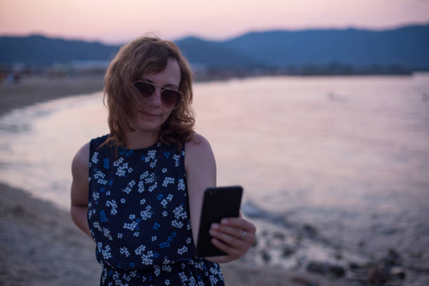 istock Woman texting on a beach on summer holiday 1211041237