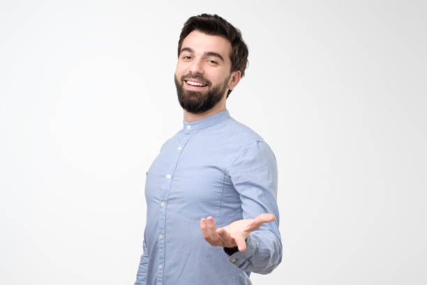 istock Hispanic young man standing smiling inviting to come in. 1211041346