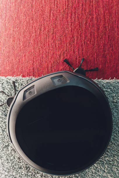 istock Robotic vacuum cleaner on carpet - technology housework. 1211046259