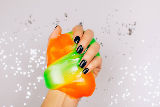 istock hands with black manicure holding slime 1211046349