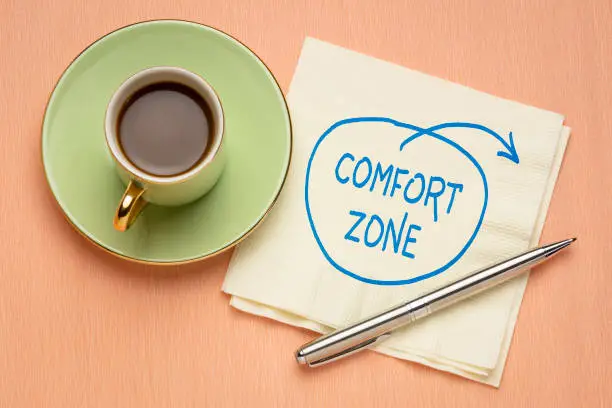 step out of comfort zone concept - motivational doodle on a napkin with a cup of coffee, challenge, motivation and personal development