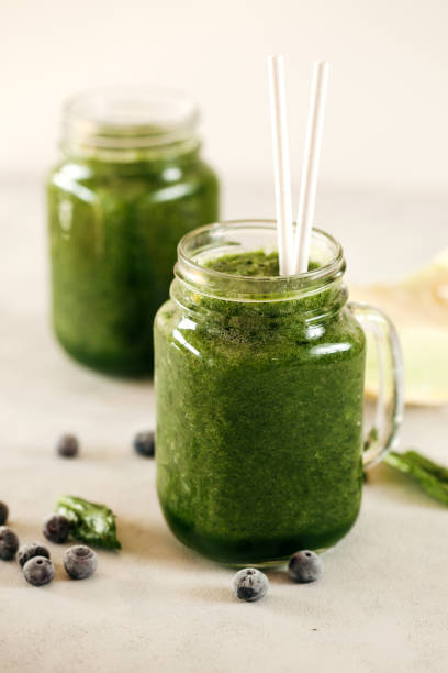 istock Green spinach leaf and blueberries smoothie on white background 1211052276