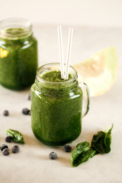 istock Green spinach leaf and blueberries smoothie on white background 1211052839