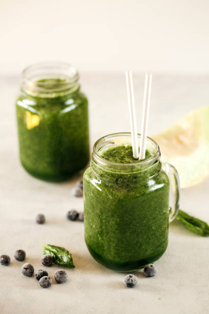 istock Green spinach leaf and blueberries smoothie on white background 1211053302