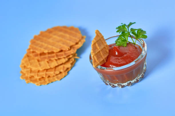 istock Piece of thin spicy waffles, savory sauce on purple background 1211063049