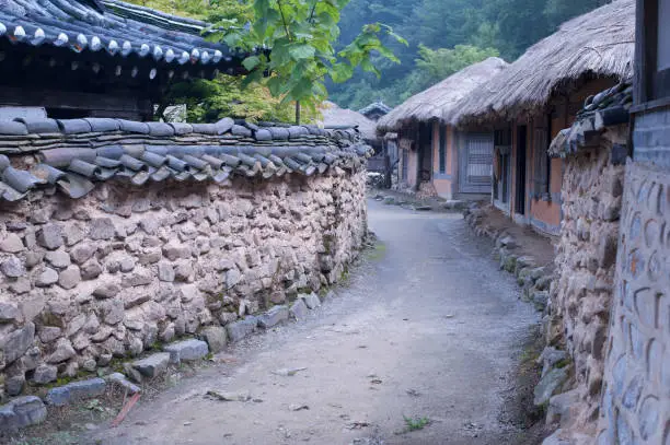 Stonewall Walkway with Traditional Korean Houses (a tile-roofed house, a house with a straw-thatched roof)