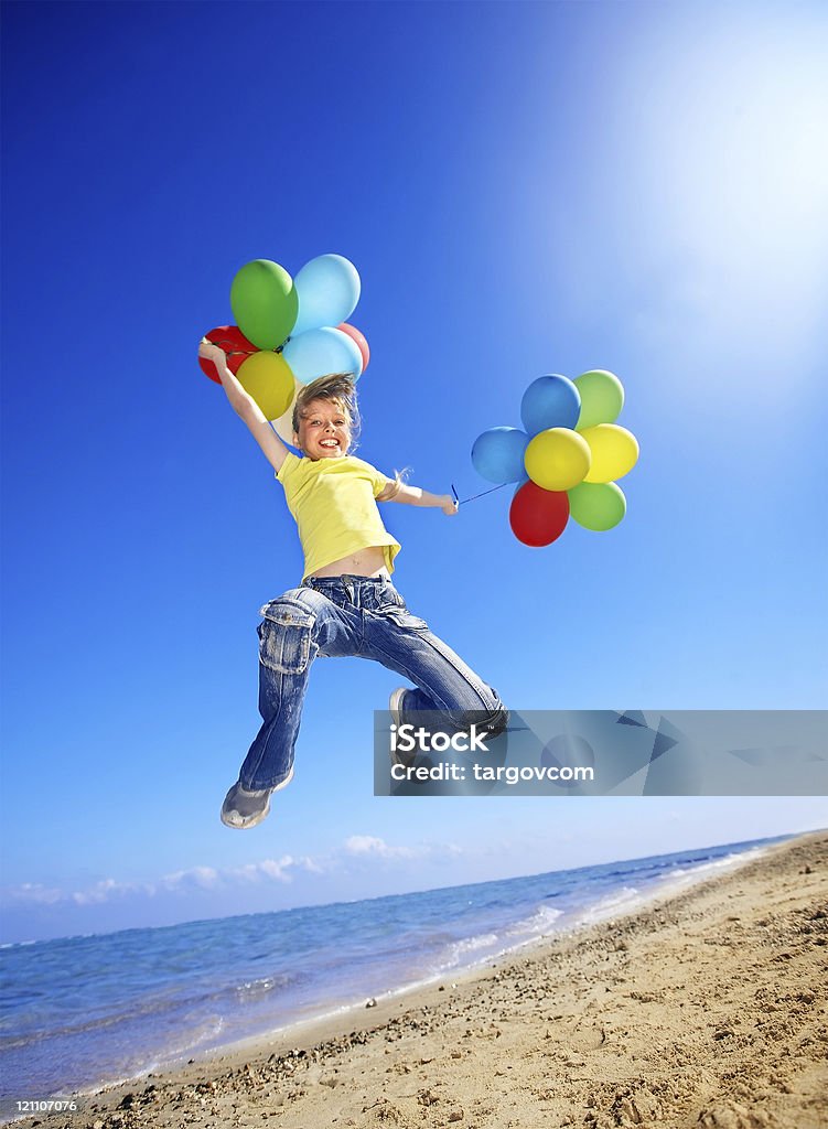Bambino che gioca con i palloncini in spiaggia - Foto stock royalty-free di Bambino