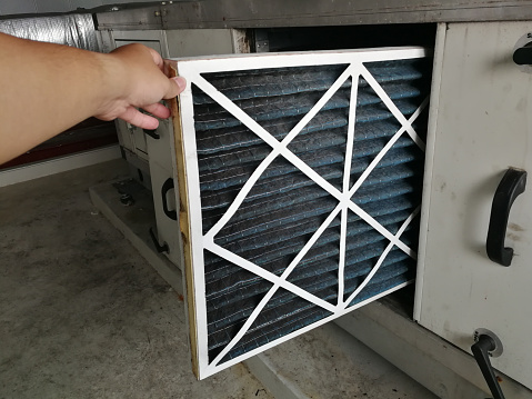 Enfoque suave al filtro de la unidad de entrega de aire, técnico que comprueba un prefiltro de la unidad de manipulación de aire para el reemplazo de un nuevo filtro - Mantenimiento HVAC photo
