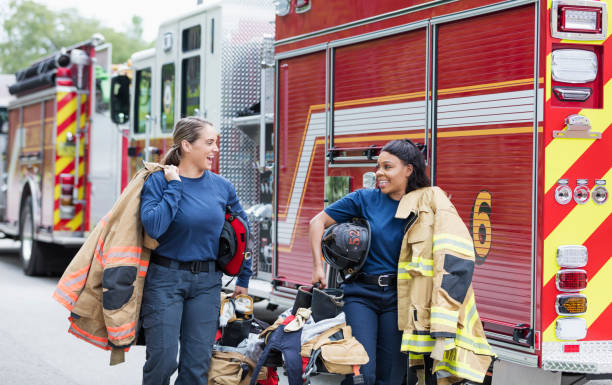 istock Two female firefighters walking next to fire trucks 1211078903