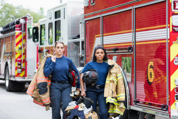 istock Two female firefighters walking next to fire trucks 1211079450