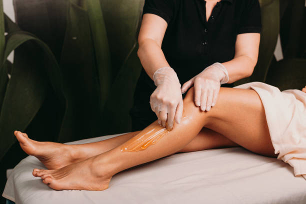 señora caucásica con hermosas piernas está teniendo una depilación de azúcar durante un procedimiento de spa profesional - leg waxing fotografías e imágenes de stock