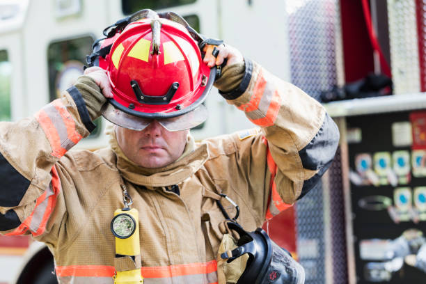 istock Firefighter in fire protection suit putting on helmet 1211079790