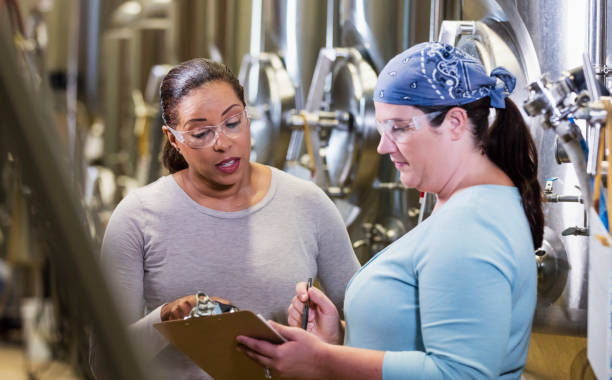 istock Two women working in factory looking at clipboard 1211080521