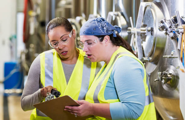 istock Two women working in factory looking at clipboard 1211080562