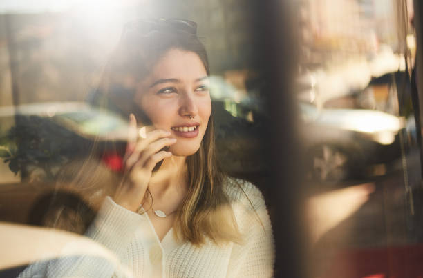 istock young girl talking by phone with reflection behind the window 1211095028
