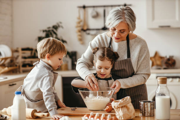 glückliche familie großmutter und enkel kochen in der küche, kneten teig, backen kekse - baking lifestyles beautiful cookie stock-fotos und bilder