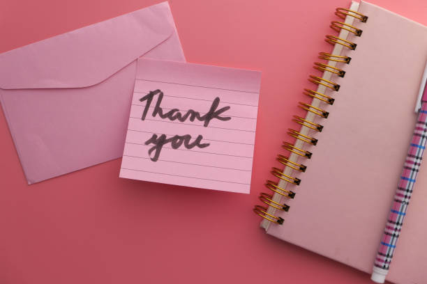 istock Close up of thank you note and envelope on pink background 1211098237
