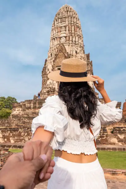 Woman holding a hand's man when visiting asian touristic ruins of Ayuthaya in Thailand