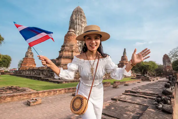 Asian woman holding a flag of thailand in the touristic ruins of Ayutthaya