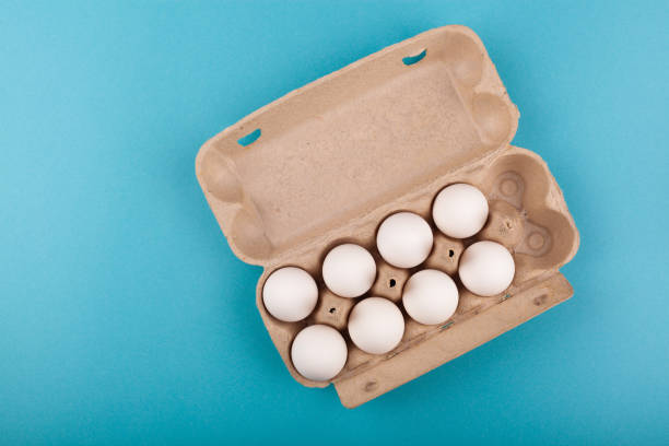 istock Egg Chicken eggs. Top view of an open gray box with white eggs. Isolated on a blue background. The concept of a healthy lifestyle, getting pure protein. Proper Breakfast. Eight eggs 1211099274