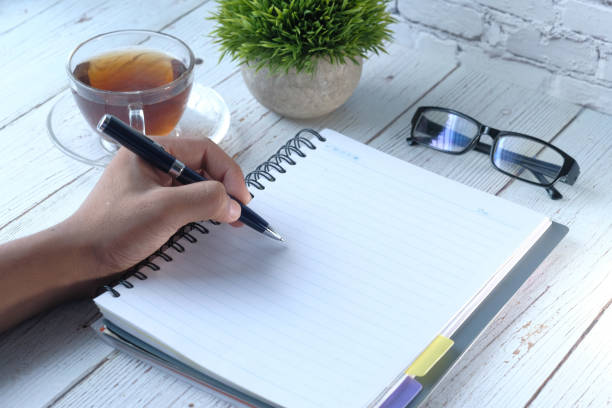 istock Close up of person hand writing on notepad 1211099620