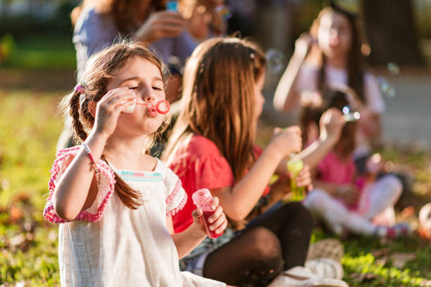 istock Happy kids blowing bubbles at public park 1211101579