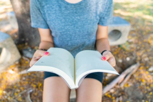 istock Hand holding a book at garden 1211101805