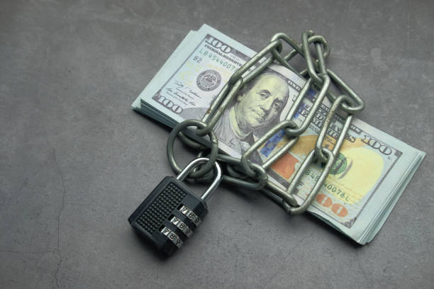 istock Folded dollar bills bound by metal chain with padlock. Business concept 1211105253