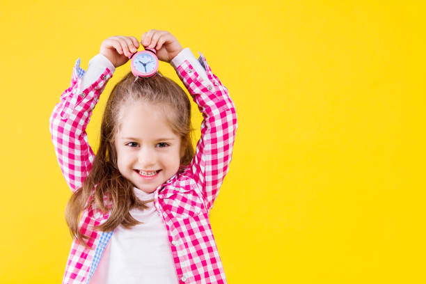 child girl in casual cloth isolated on yellow background - clock face clock deadline human hand imagens e fotografias de stock