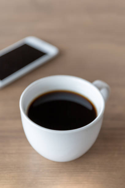 istock hot coffee cup on wooden table with soft-focus and over light in the background 1211105985