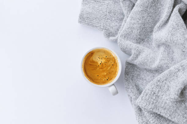 istock winter concept. cup of coffee with  sweater on white table background. top view 1211105987