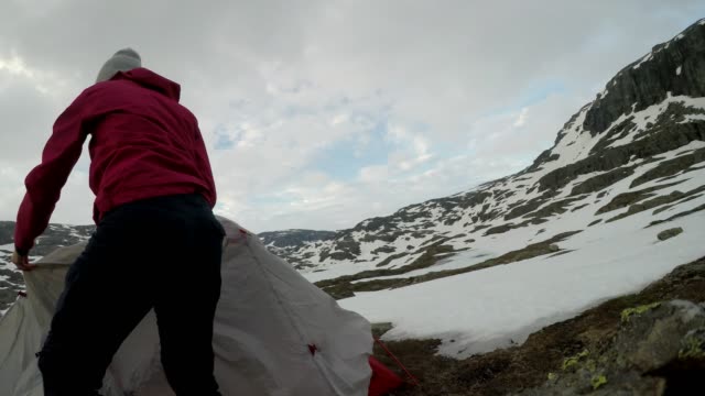 Norway - A girl putting up a tent in the wilderness