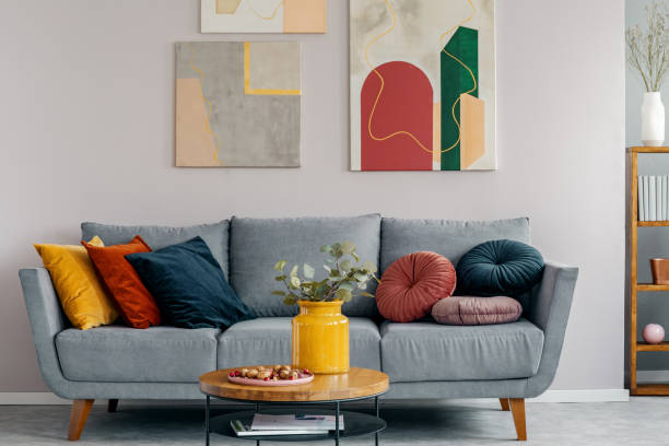 bức tranh trừu tượng đầy màu sắc phía trên chiếc ghế dài màu xám với gối trong nội thất thiết kế scandinavian - autumn living room decor hình ảnh sẵn có, bức ảnh & hình ảnh trả phí bản quyền một lần