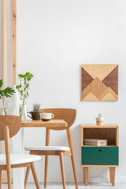 istock Green plants in small vases on long wooden dining table in bright interior 1211111444