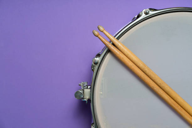 istock Drum stick and drum on purple table background, top view, music concept 1211111469