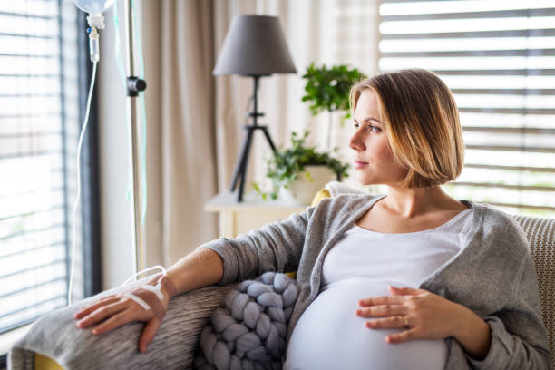 un retrato de mujer embarazada con goteo intravenoso en casa o en el hospital. - solución salina fotografías e imágenes de stock