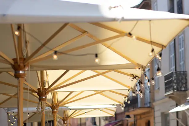 Outdoor terrace of a cafeteria in the old part of Ravenna with the awning full of bulbs lights on. Midday sunlight. Outdoor photography. Without people