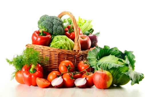 Variety of raw vegetables in wicker basket isolated on white background