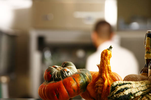 close pumpkin in a row in kitchen as a decoration with a cook in background