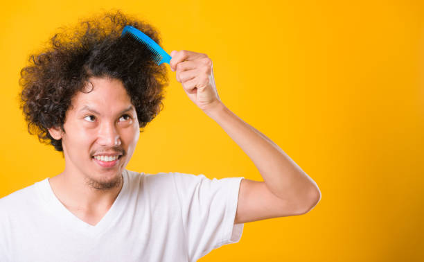 istock Asian man combing curly hair on yellow background 1211116288
