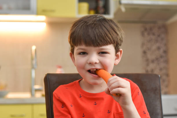 istock Six year old boy eat a fresh carrot 1211116339
