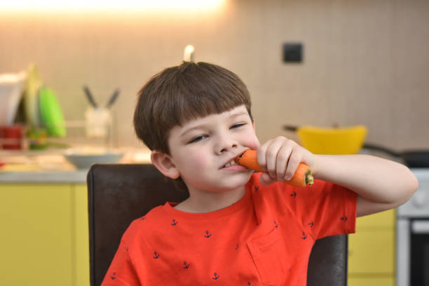 istock Six year old boy eat a fresh carrot 1211116388