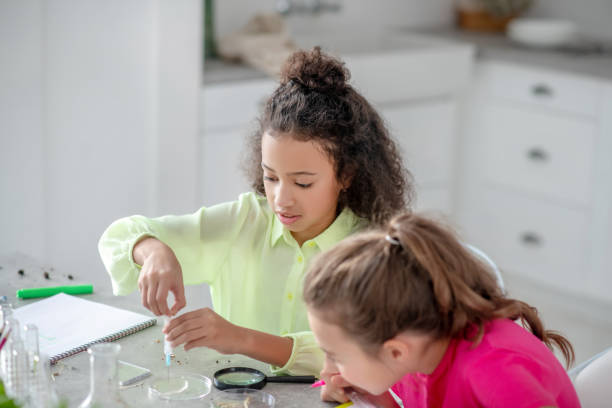 istock Two girls sitting at the table conducting an experiment. 1211120657