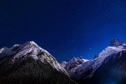 Majestic mountains landscape at night against clear sky with stars.