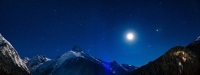 Majestic mountains landscape at night against clear sky with stars. Panoramic shot starched of 5 separate images